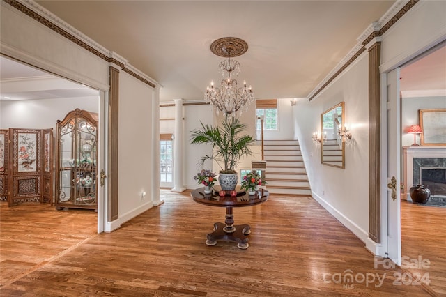 entryway featuring a high end fireplace, crown molding, a chandelier, and hardwood / wood-style flooring