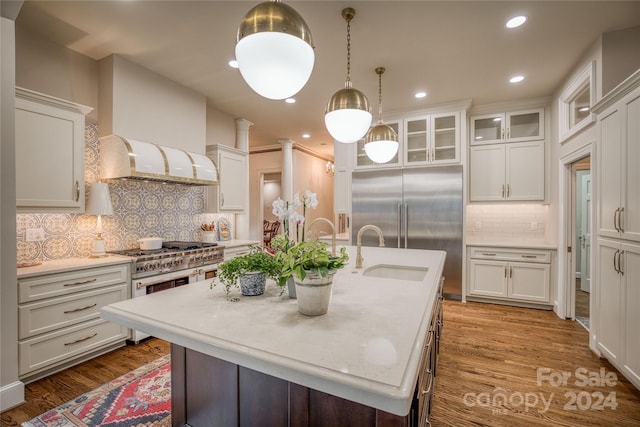 kitchen featuring an island with sink, tasteful backsplash, dark wood-type flooring, and sink