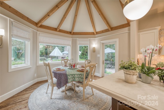 dining room featuring high vaulted ceiling, beam ceiling, and light hardwood / wood-style floors