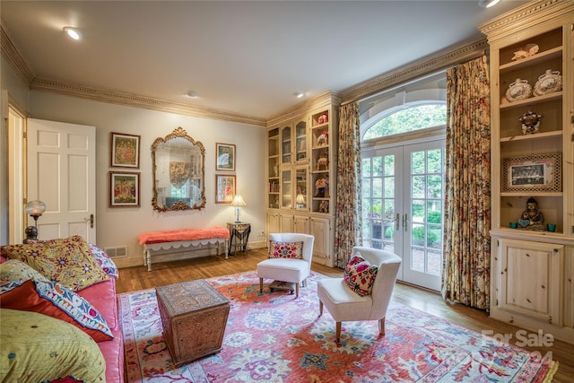 living area with light wood-type flooring, crown molding, and french doors