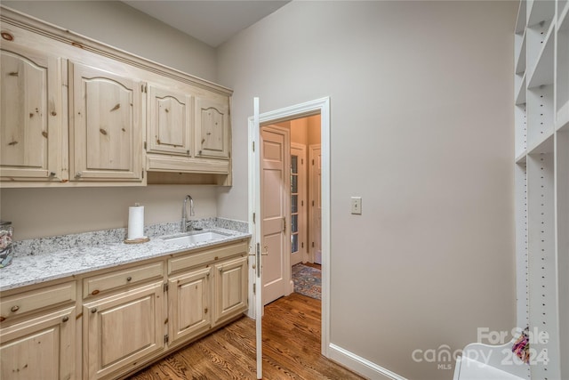 interior space featuring light stone counters, light brown cabinets, sink, and hardwood / wood-style floors