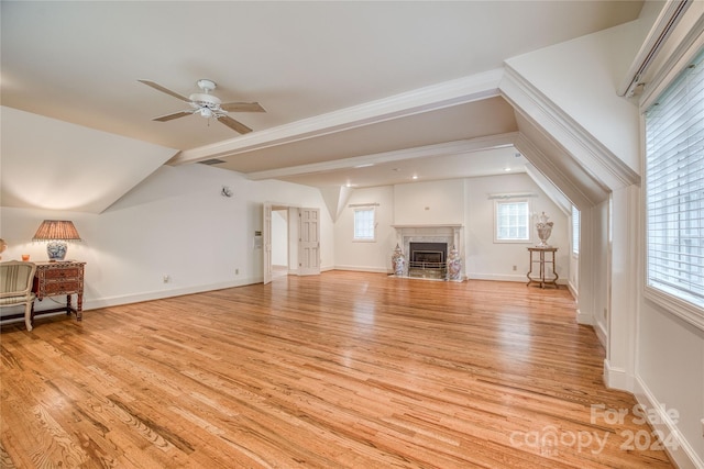 living room with vaulted ceiling with beams, ceiling fan, light hardwood / wood-style flooring, and a premium fireplace