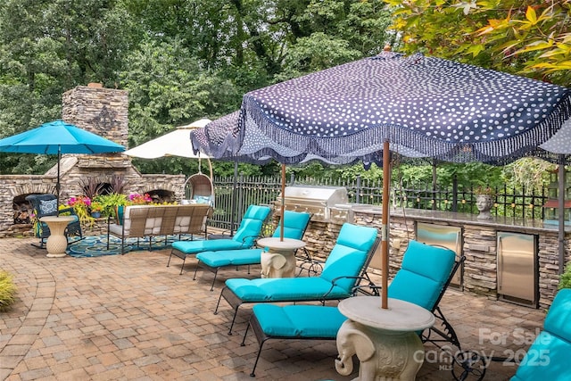 view of patio / terrace with an outdoor living space with a fireplace, a grill, fence, and exterior kitchen