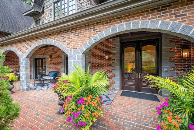 view of exterior entry featuring french doors and brick siding