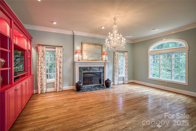 unfurnished living room with a high end fireplace, crown molding, baseboards, and wood finished floors