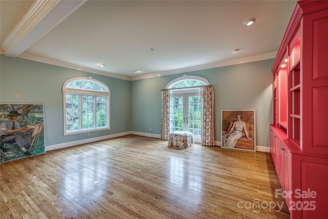 spare room featuring crown molding, baseboards, and light wood-style floors