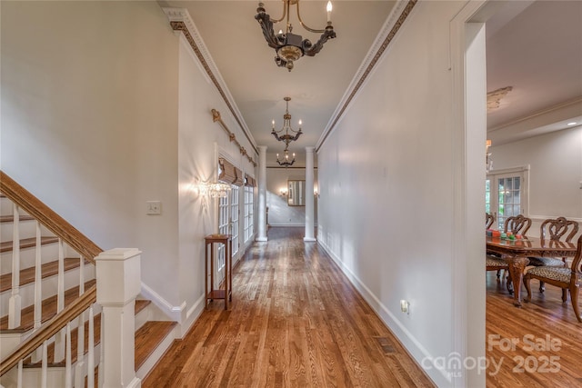 hall with crown molding, stairs, a notable chandelier, and wood finished floors