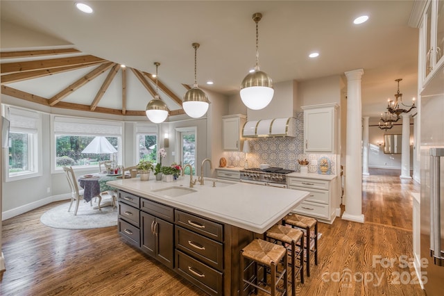 kitchen with a breakfast bar, high end stainless steel range, light countertops, ornate columns, and a sink