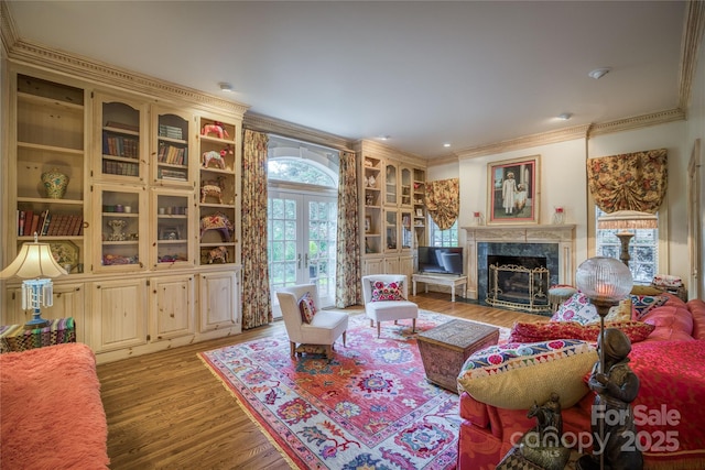 living area featuring a high end fireplace, ornamental molding, wood finished floors, and french doors