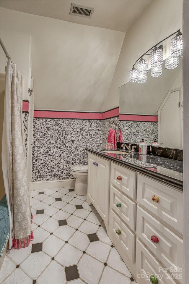 bathroom with visible vents, toilet, lofted ceiling, tile patterned floors, and vanity