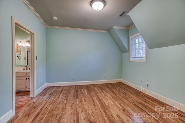 bonus room featuring lofted ceiling, a sink, wood finished floors, visible vents, and baseboards