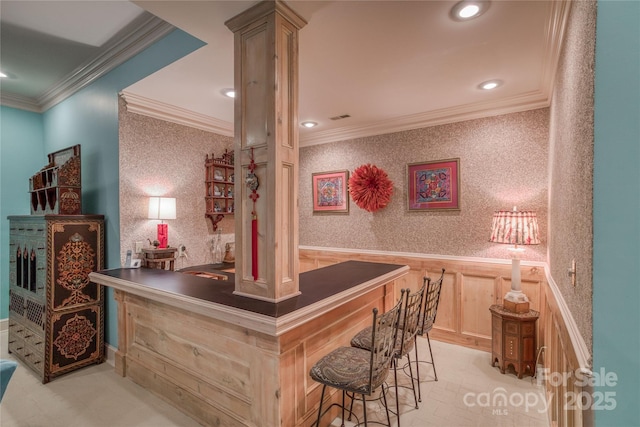 bar with wallpapered walls, ornamental molding, and a wainscoted wall