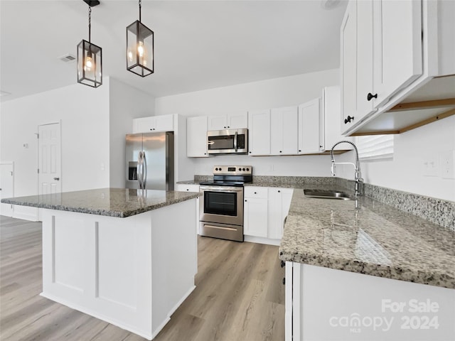 kitchen with stone countertops, a kitchen island, stainless steel appliances, and white cabinets