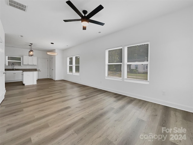 unfurnished living room featuring ceiling fan, light hardwood / wood-style floors, and sink