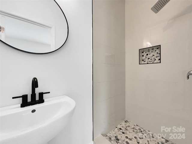 bathroom featuring a tile shower and sink