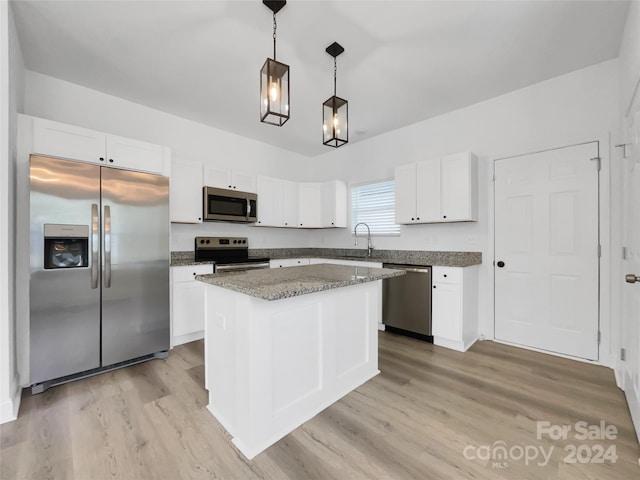 kitchen with stone counters, light hardwood / wood-style flooring, decorative light fixtures, a center island, and appliances with stainless steel finishes