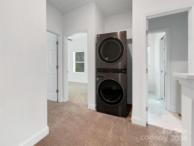 clothes washing area with stacked washing maching and dryer and light colored carpet