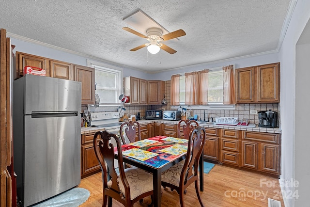 kitchen with light wood-type flooring, stainless steel fridge, plenty of natural light, and ceiling fan