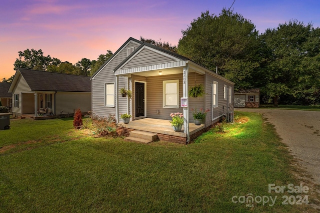 bungalow featuring an outdoor structure, a porch, a yard, and central air condition unit