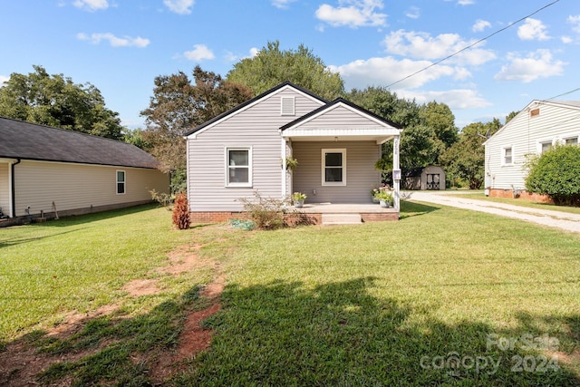 view of front of house with a front yard, an outdoor structure, and a porch