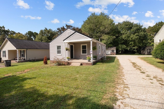 bungalow-style home with driveway, a shed, an outbuilding, a front lawn, and a porch