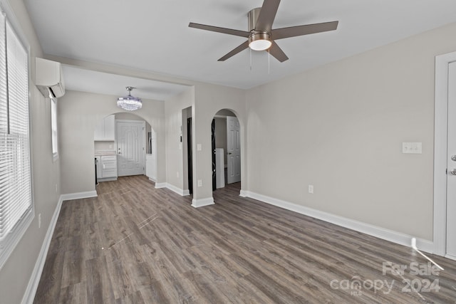 unfurnished living room featuring baseboards, ceiling fan, wood finished floors, arched walkways, and an AC wall unit