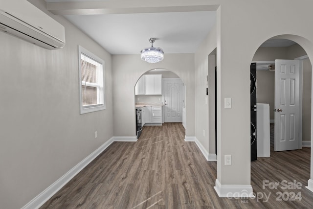 hall with dark wood-style floors, a wall unit AC, arched walkways, and baseboards