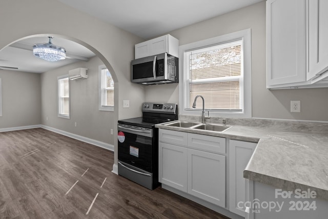 kitchen featuring a wall unit AC, dark wood finished floors, a sink, arched walkways, and appliances with stainless steel finishes