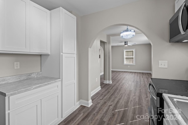 kitchen featuring ceiling fan, stainless steel microwave, arched walkways, white cabinetry, and black electric range oven