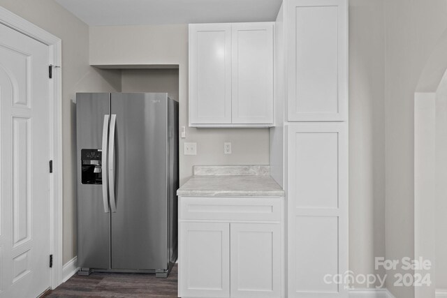 kitchen with stainless steel refrigerator with ice dispenser, dark wood-type flooring, and white cabinetry