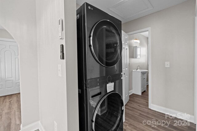 laundry area with stacked washer and dryer and hardwood / wood-style flooring