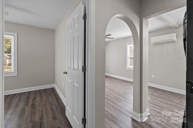 corridor featuring baseboards, a wall mounted AC, and wood finished floors