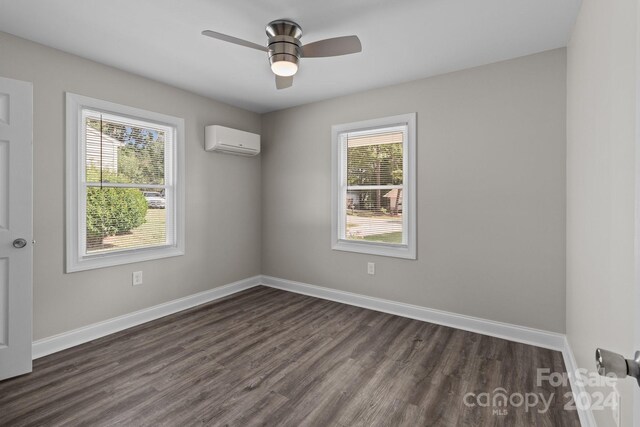 spare room featuring ceiling fan, dark hardwood / wood-style floors, and a wall unit AC