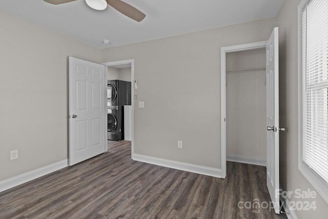 unfurnished bedroom with stacked washer / dryer, dark wood-type flooring, a closet, and baseboards