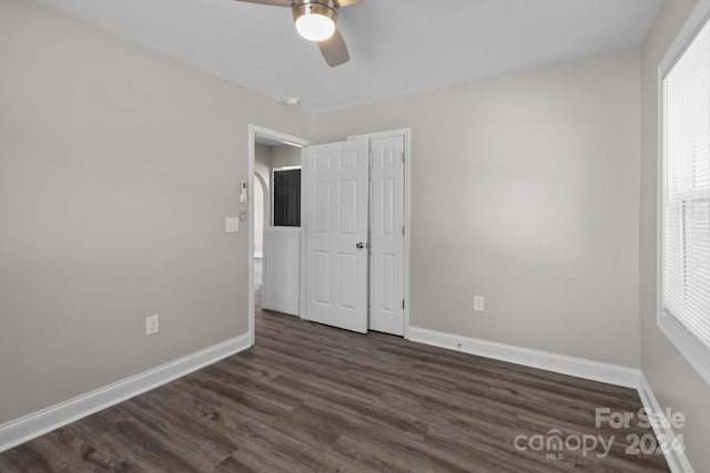 unfurnished bedroom featuring ceiling fan, dark hardwood / wood-style flooring, and multiple windows