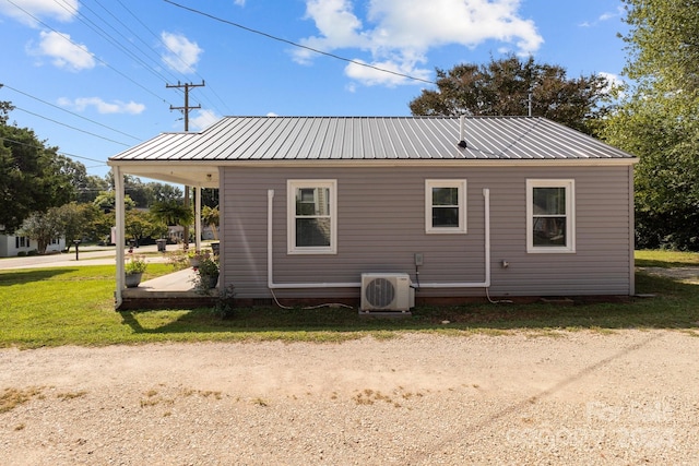 back of property with ac unit, a lawn, and metal roof