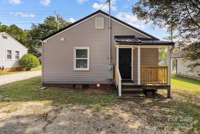 rear view of property featuring a yard and metal roof
