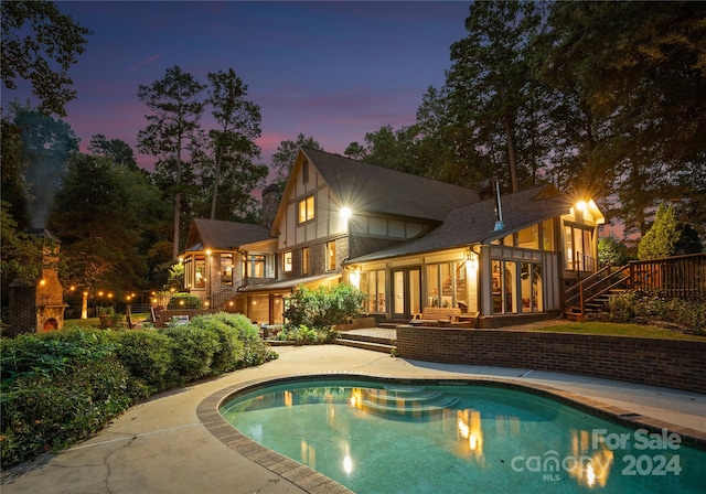 back house at dusk with a patio and a swimming pool side deck