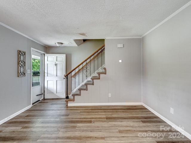 foyer with a textured ceiling, light hardwood / wood-style flooring, and ornamental molding