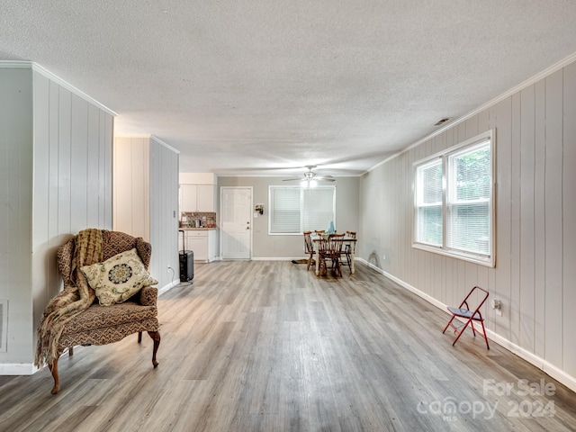 sitting room featuring light wood-type flooring, crown molding, and a textured ceiling