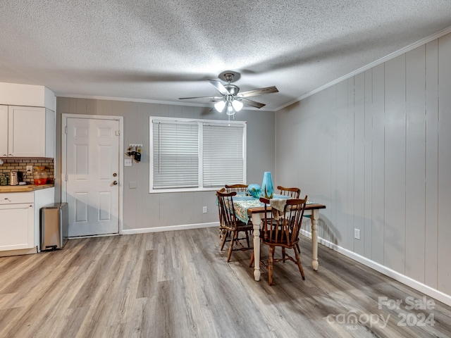 dining area with light wood-type flooring, ceiling fan, crown molding, and a textured ceiling