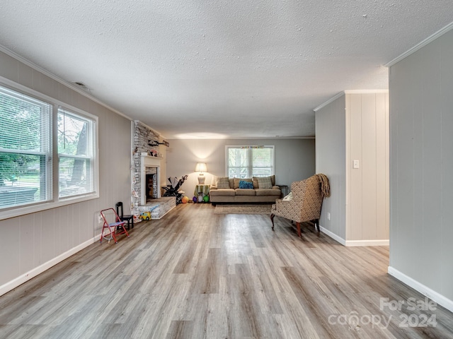 living room with crown molding, a fireplace, light hardwood / wood-style flooring, and plenty of natural light