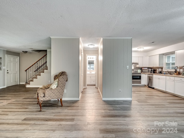 kitchen featuring tasteful backsplash, a textured ceiling, white cabinetry, appliances with stainless steel finishes, and light wood-type flooring