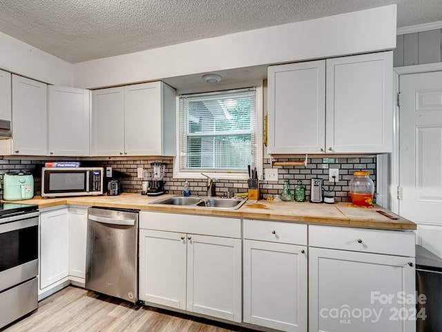 kitchen with appliances with stainless steel finishes, decorative backsplash, sink, and white cabinets