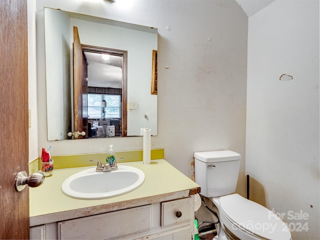 bathroom with a textured ceiling, vanity, and toilet