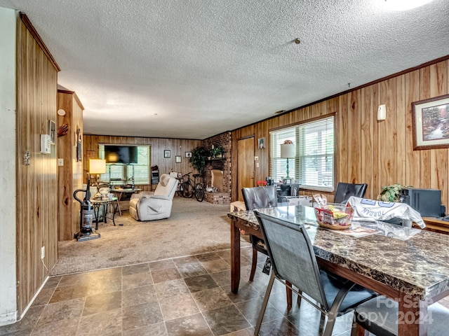 dining area featuring a textured ceiling, crown molding, wooden walls, and dark carpet