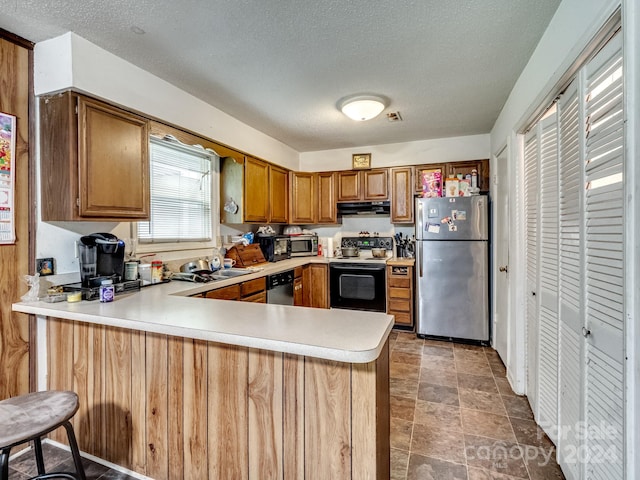 kitchen featuring stainless steel appliances, kitchen peninsula, sink, and a textured ceiling