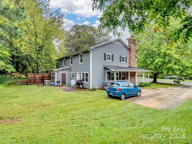 rear view of property with a yard and central air condition unit