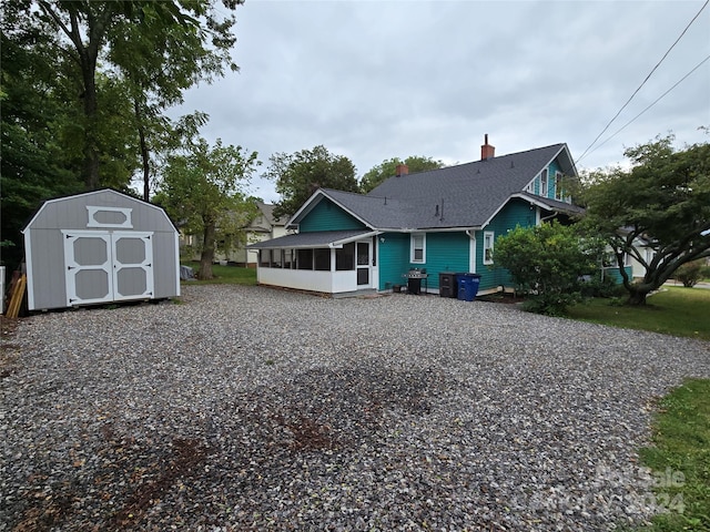 rear view of property featuring a storage unit and a sunroom