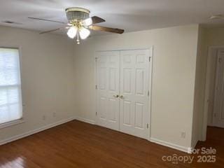 unfurnished bedroom with dark hardwood / wood-style floors, ceiling fan, and a closet